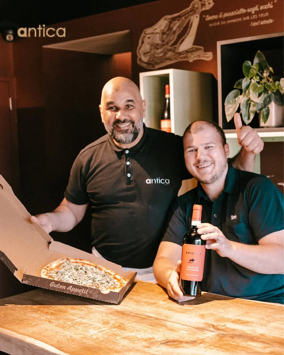 Les mains du pizzaiolo garnissant une pizza sur le plan de travail