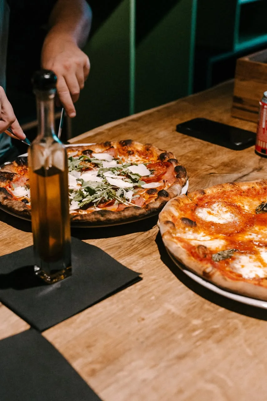 L’huile d’olive et deux pizzas sur la planche